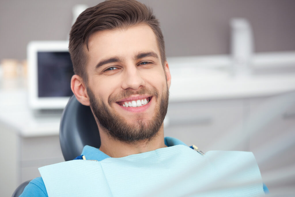 man smiling while sitting in the dental chair